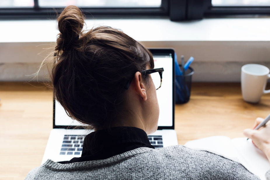 female-taking-notes-and-browsing-laptop